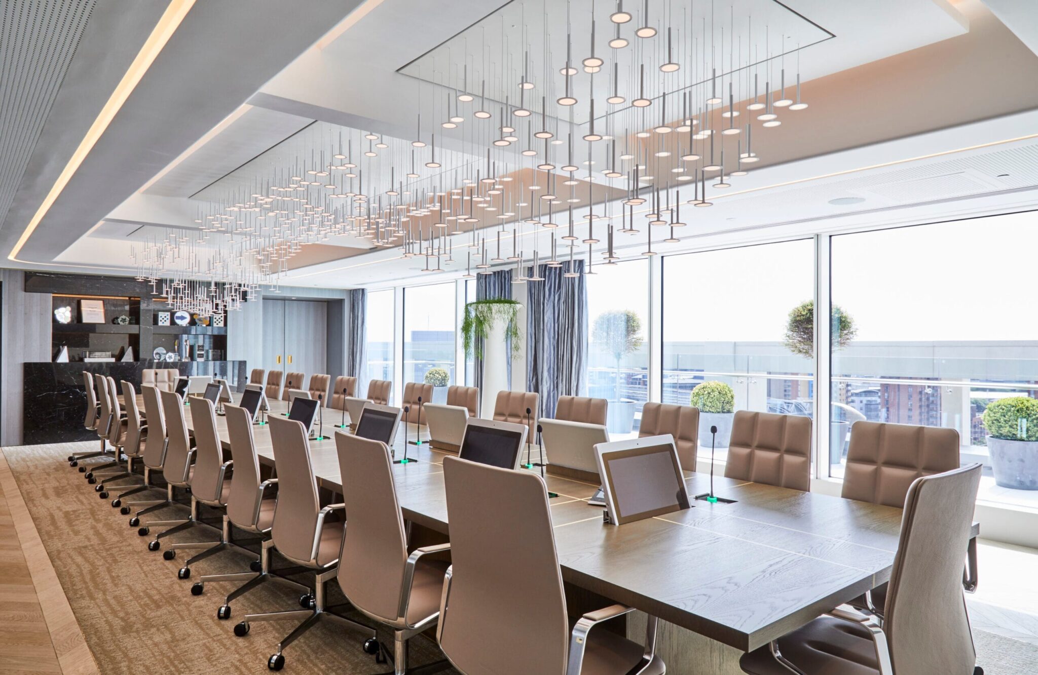 Boardroom lighting design with statement ceiling fixtures and recessed lights creating a bright, modern corporate meeting space.