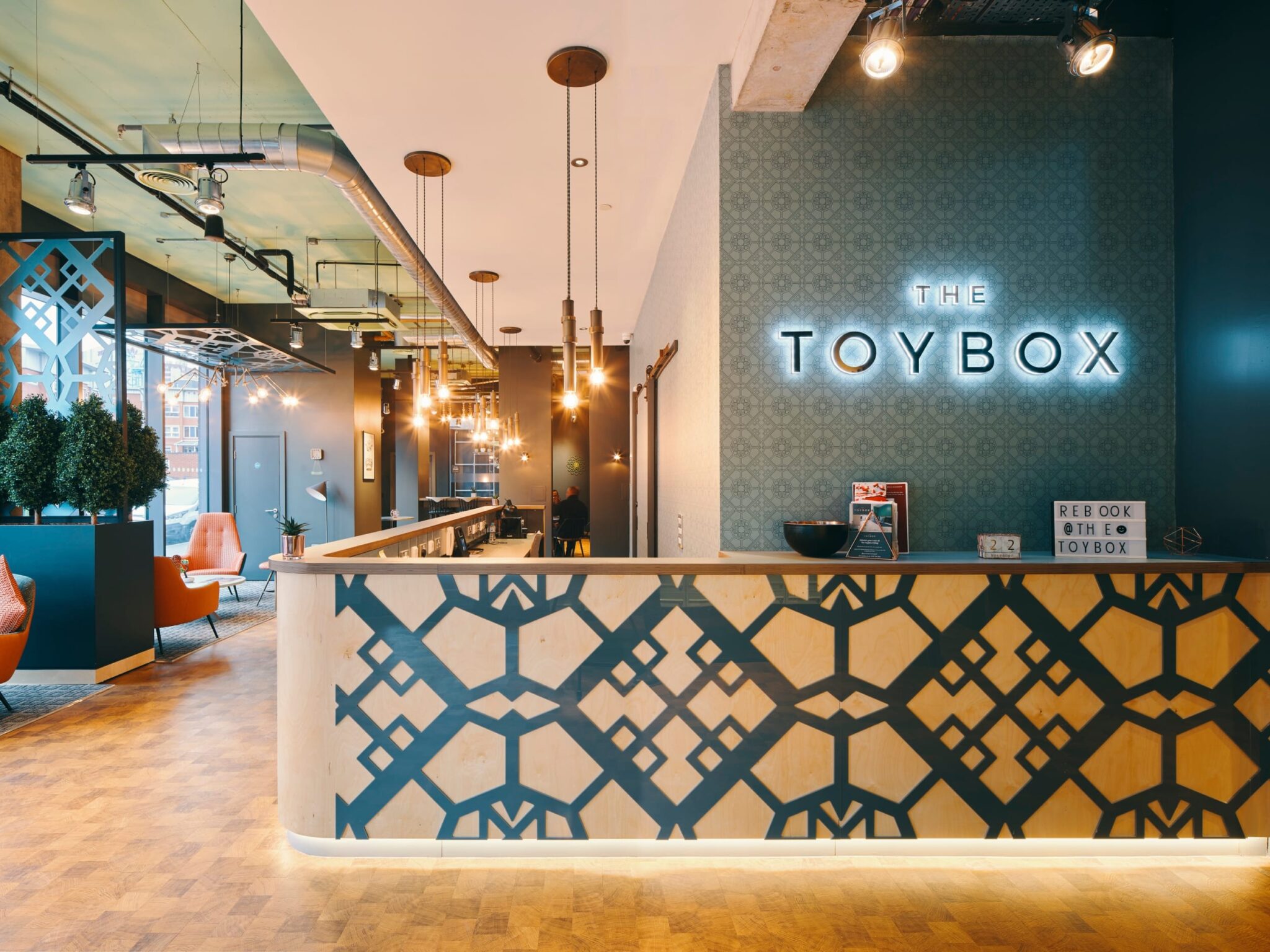 Reception lighting design with hanging bulbs, neon signage, and under-desk lighting at The Toybox