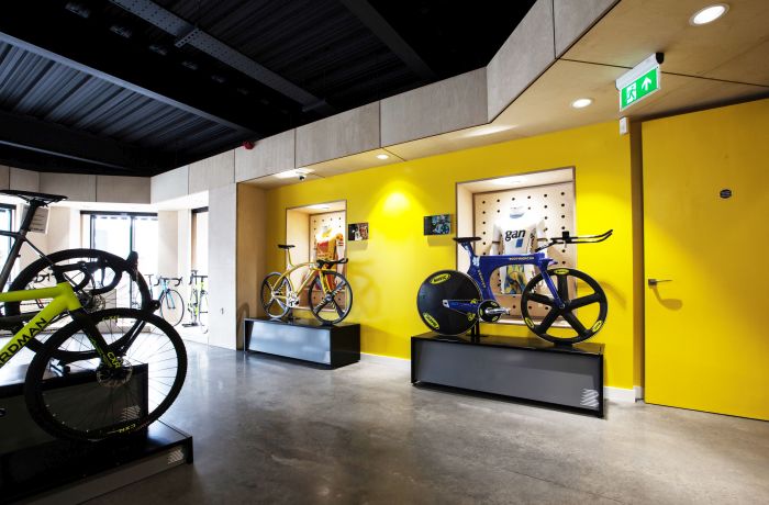 Retail lighting design with recessed spotlights highlighting bicycle displays against a bold yellow wall.