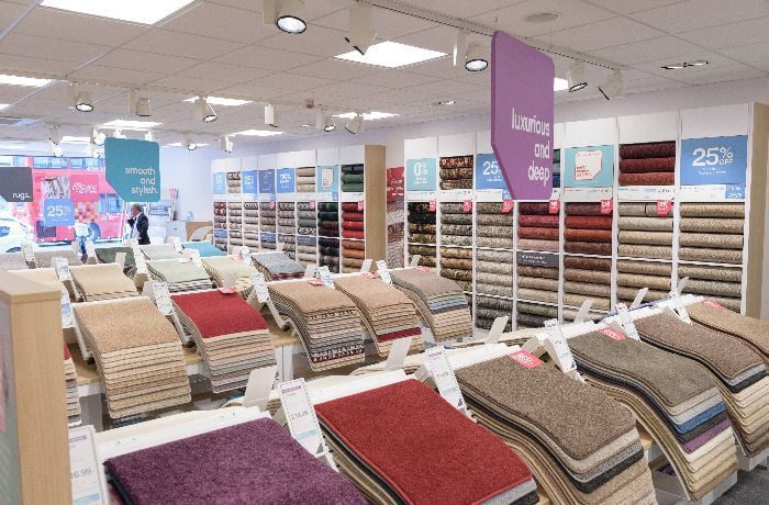 Retail lighting design with ceiling spotlights and recessed fixtures illuminating a carpet showroom display.