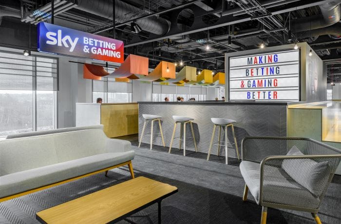 Office lighting design with track lighting and accent features illuminating a branded breakout space.
