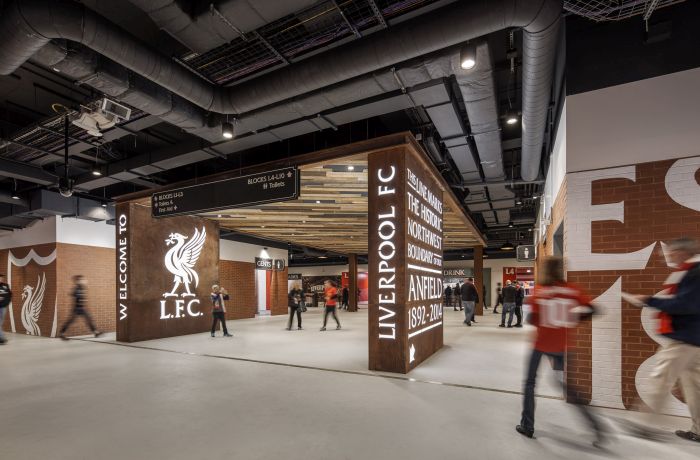 Stadium concourse with illuminated signage, recessed downlights, and LED strip lighting.