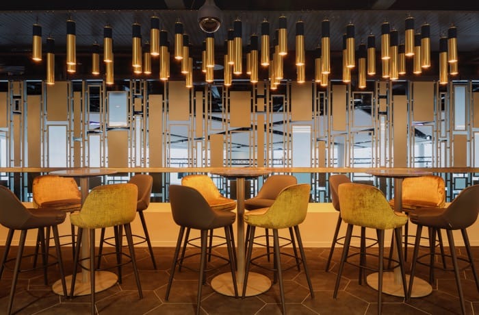 Bar lighting design with cylindrical hanging lights creating a warm and stylish lounge atmosphere.