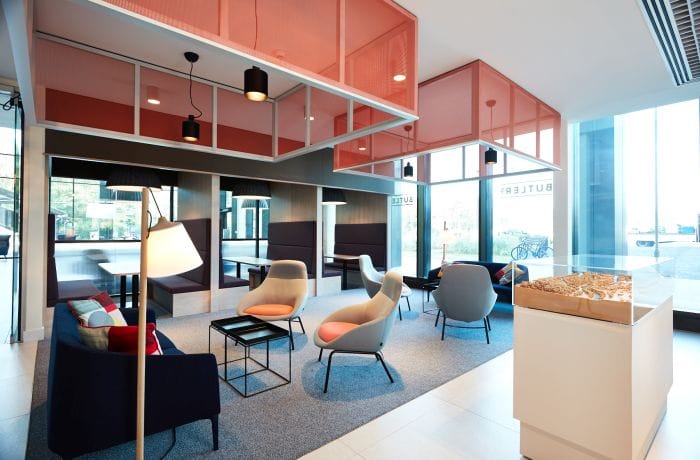 Office lighting design with pendant and floor lamps complementing natural daylight in a colorful modern lounge area.