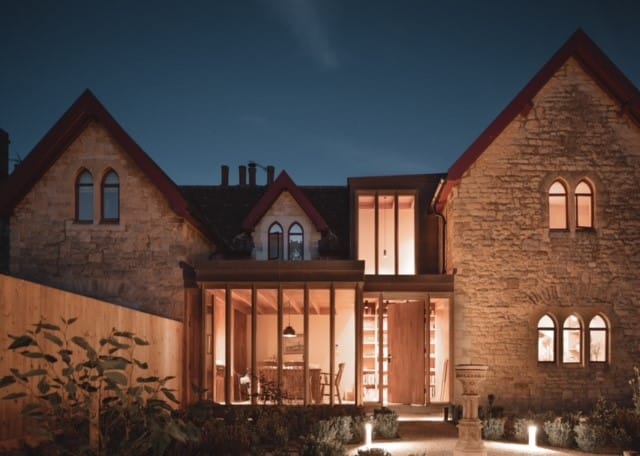 Residential exterior lighting design highlighting the stone façade and entrance of a house at night.
