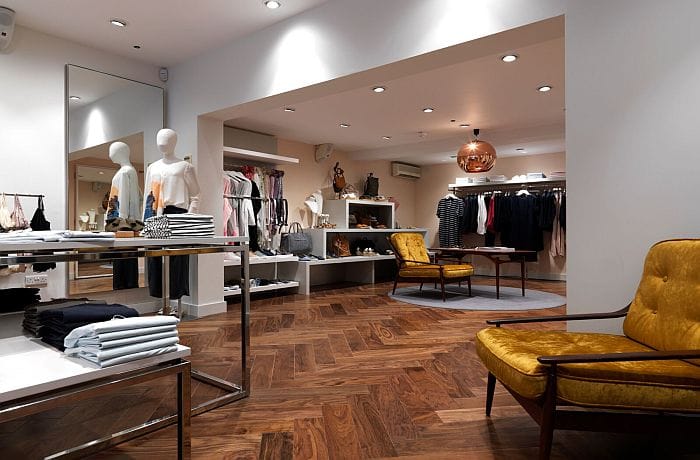 Boutique with recessed spotlights and a copper pendant illuminating clothing displays